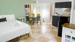 A hotel room with a bed, a desk, a chair, a mirror, a kitchenette, and a bathroom. - CH 1003: Cozy studio with kitchenette, WiFi & Pool, CH 1003: Cozy studio in amazing Manatí with AC, ... (Tierras Nuevas Saliente)
