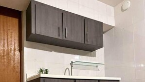 A kitchen with dark cabinets, a white countertop, and a glass shelf. - CH 1003: Cozy studio with kitchenette, WiFi & Pool, CH 1003: Cozy studio in amazing Manatí with AC, ... (Tierras Nuevas Saliente)