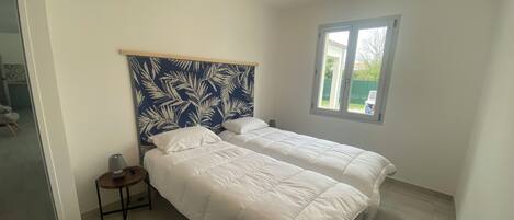 A bedroom with two beds, a nightstand, a window, and a ceiling light.