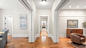 A modern interior with a wooden floor, a dining area with chairs, a sofa, and a fireplace in the background. - 10 Mins to Mercedes-Benz Stadium | Dog Friendly (Atlanta)