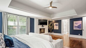 A modern bedroom with a large bed, a seating area, a fireplace, and a television. - 10 Mins to Mercedes-Benz Stadium | Dog Friendly (Atlanta)