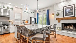 A modern kitchen with white cabinets, a large island, and a fireplace. - 10 Mins to Mercedes-Benz Stadium | Dog Friendly (Atlanta)