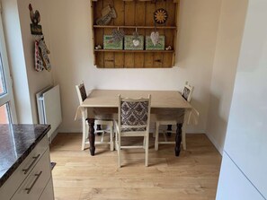 A dining area with a wooden table and chairs, a radiator, and a shelf with decorative items. - Beautiful home near to Musgrove Park Hospital (Taunton)