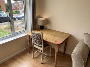 A room with a wooden table, a chair, a lamp, and a window overlooking a street. - Beautiful home near to Musgrove Park Hospital (Taunton)