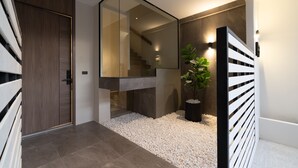 A modern interior with a wooden door, a glass wall, and a staircase. - 5min to Beach/Bangla - Luxury 3BR Townhome + Pool (ตำบลป่าตอง)