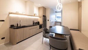 A modern kitchen with a central island, a dining area with a black marble table, and a built-in oven. - 5min to Beach/Bangla - Luxury 3BR Townhome + Pool (ตำบลป่าตอง)