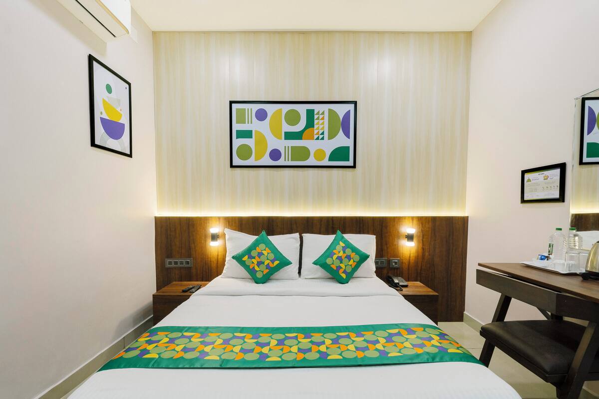 A hotel room with a bed, two bedside tables, a desk, and a chair.