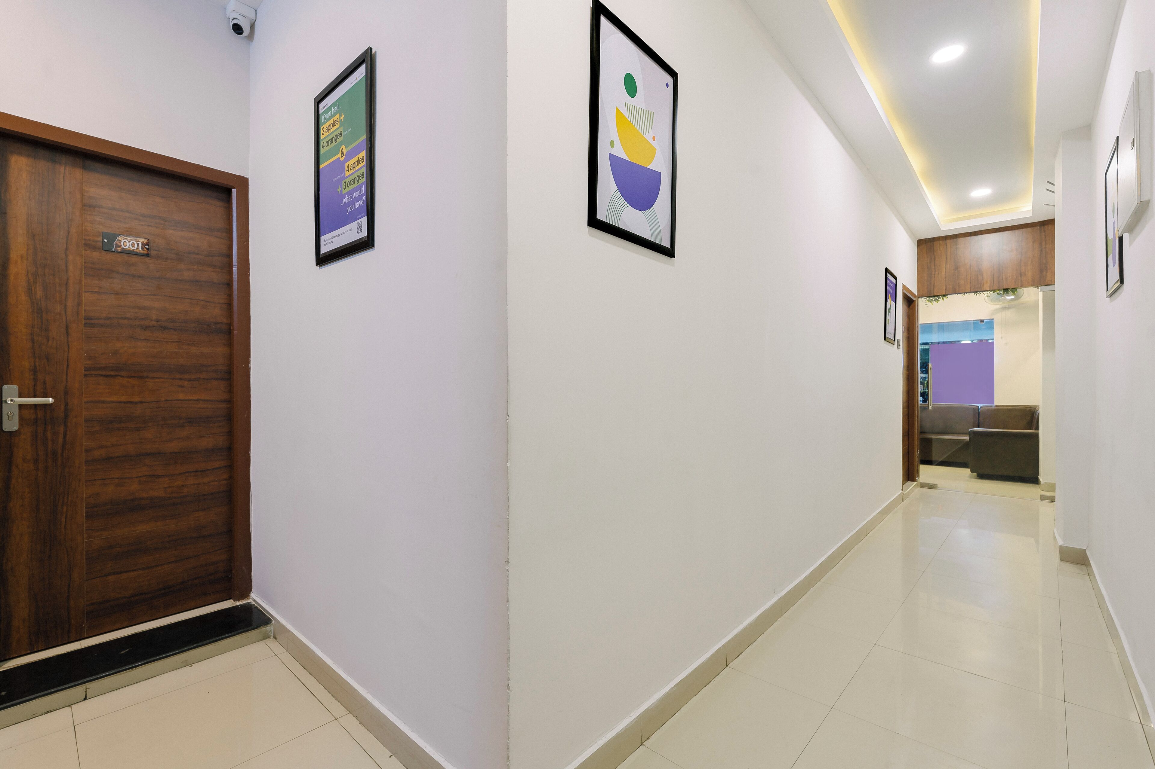 A hallway with a wooden door labeled "SOUT", a framed abstract artwork, and a purple wall in the distance.