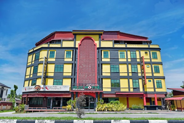 A multi-story hotel with a prominent red and yellow facade, multiple balconies, and a large arched entrance. - Hotel O Rayyan Soffea Managed by Oravel (Kota Bharu)