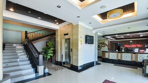 A hotel lobby with a staircase, reception desk, and a large plant. - Hotel O Rayyan Soffea Managed by Oravel (Kota Bharu)
