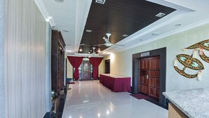 A hotel corridor with a marble floor, red curtains, a reception desk, and a ceiling with recessed lighting and fans. - Hotel O Rayyan Soffea Managed by Oravel (Kota Bharu)
