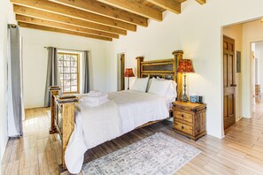 Un dormitorio con cama de madera, una mesita de noche, una lámpara y una ventana con cortinas.