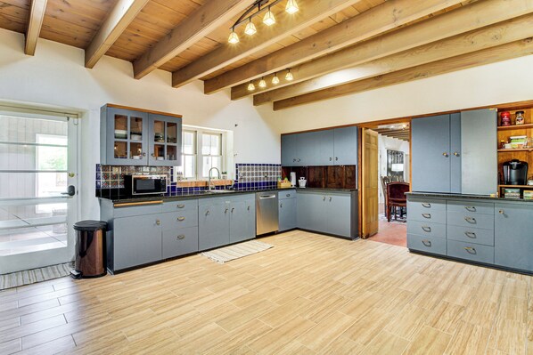 A spacious kitchen with wooden beams, grey cabinets, and a tiled backsplash. - Balloon Fiesta By Day, Private Pool By Afternoon (Albuquerque)