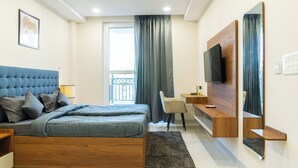 Een moderne slaapkamer met een bed, bureau, stoel en televisie.