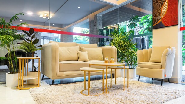 Een moderne woonkamer met een beige bank, twee bijpassende fauteuils, een salontafel en potplanten.