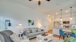 A modern living room with a grey sofa, a coffee table, and a dining area with blue chairs.