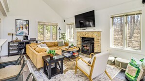 A cozy living room with a stone fireplace, a large TV, and a comfortable sofa. - Steps to Jack Frost Ski Resort: Townhome w/ Decks (White Haven)