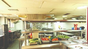 A buffet area with labeled sections for Chinese and Indian cuisine, stainless steel serving counters, and various vegetables. - Hotel Indraprastha Kayamkulam (Kayamkulam)