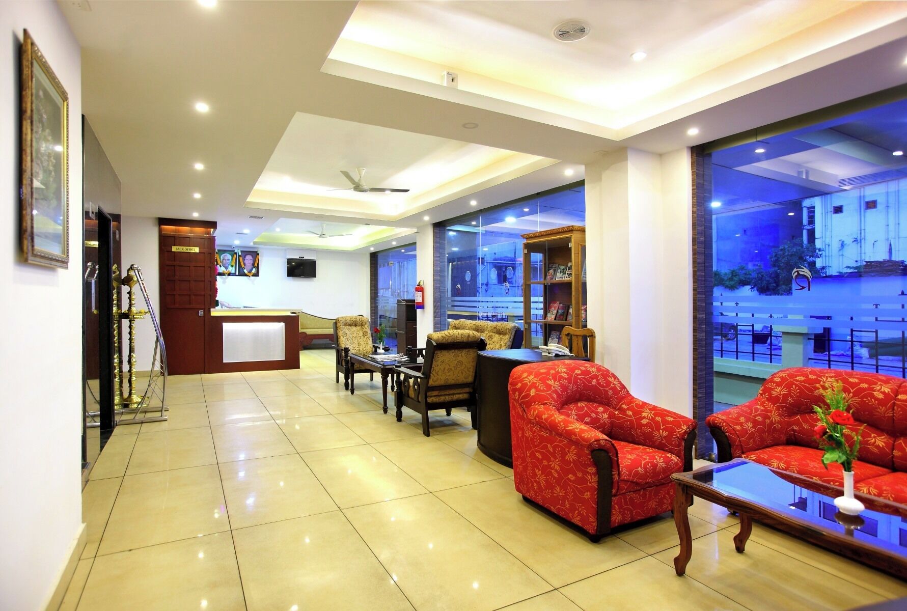 A hotel lobby with a reception desk, seating area, and large windows offering a view of the outside.