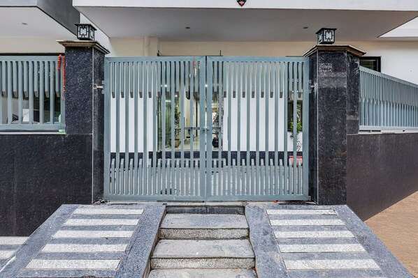 A gated entrance with a metal gate, steps leading up to the gate, and a small pathway. - The Byke Business Hotel - Sector 29 (Gurugram)