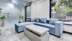 A modern living room with a sectional sofa, a coffee table, and potted plants. - The Byke Business Hotel - Sector 29 (Gurugram)