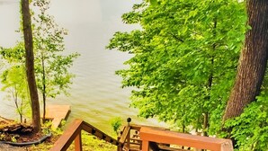 Une terrasse en bois avec une rambarde donnant sur une étendue d’eau, entourée d’arbres.