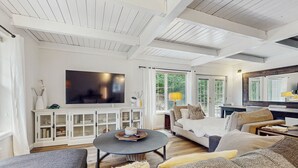 A spacious living room with a large TV, white cabinets, a sofa, and a coffee table.