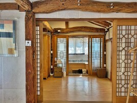 Un interior japonés tradicional con vigas de madera, puertas correderas y una zona de estar central.