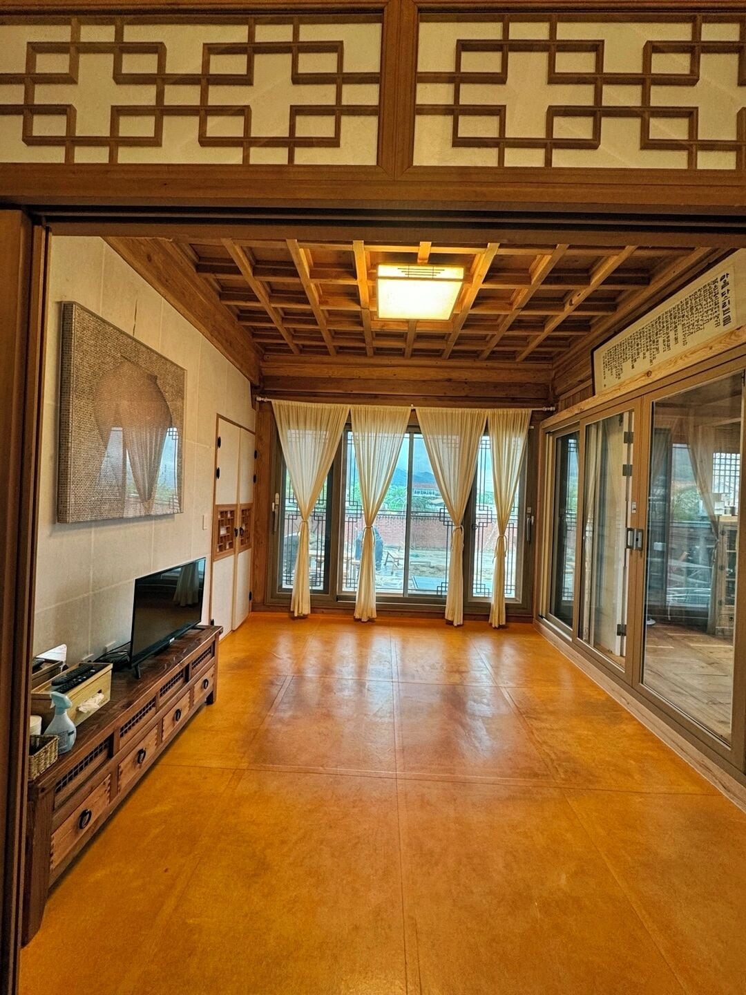 Una habitación tradicional japonesa con suelo de tatami, puertas correderas y un televisor sobre un soporte de madera.