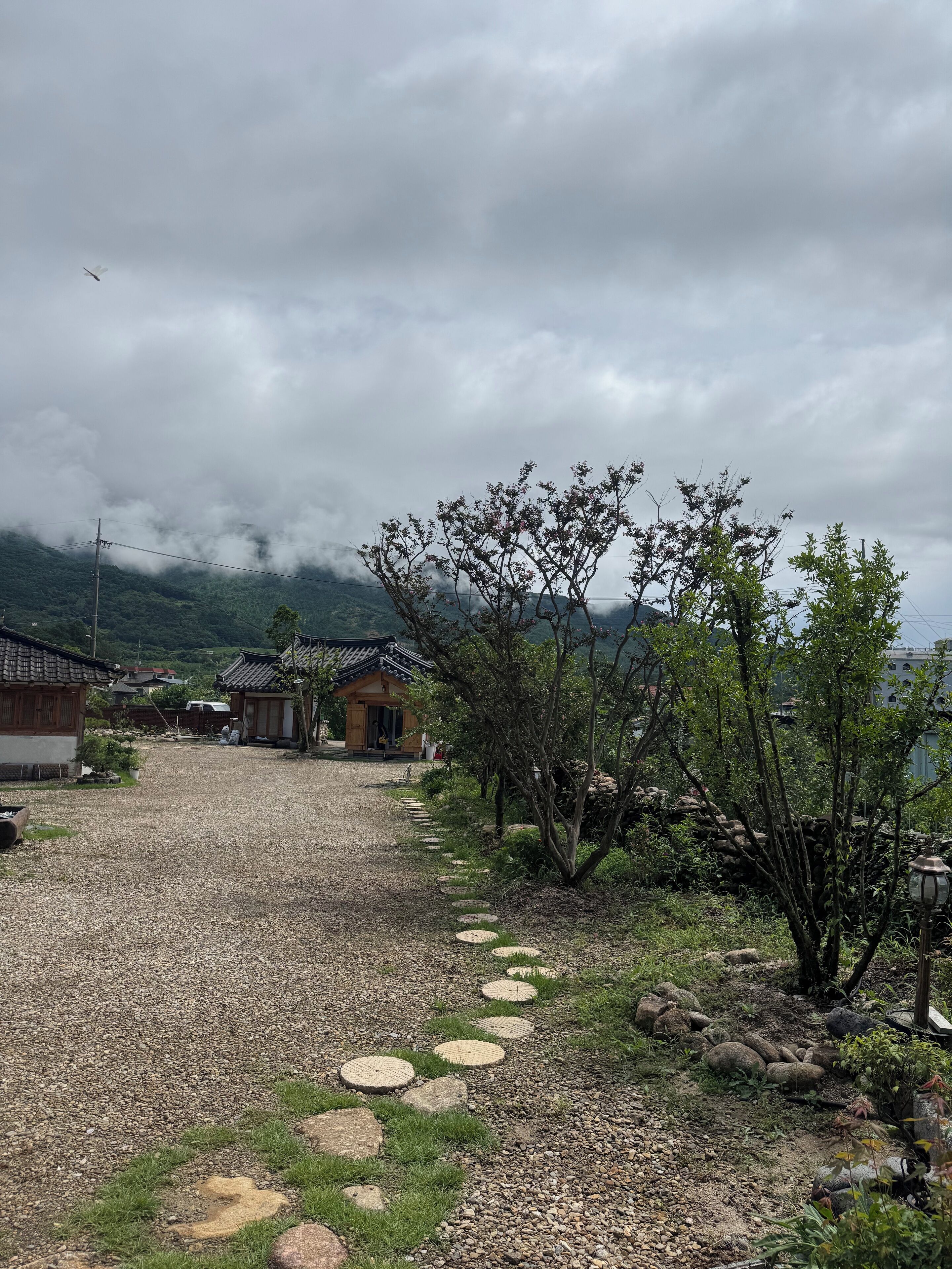 A traditional village with stone pathways, wooden houses, and a mountainous backdrop.