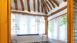 A wooden cabin with a stone bathtub, wooden benches, and a pair of slippers. - Jukrokjungsa hanokstay  (Gurye)