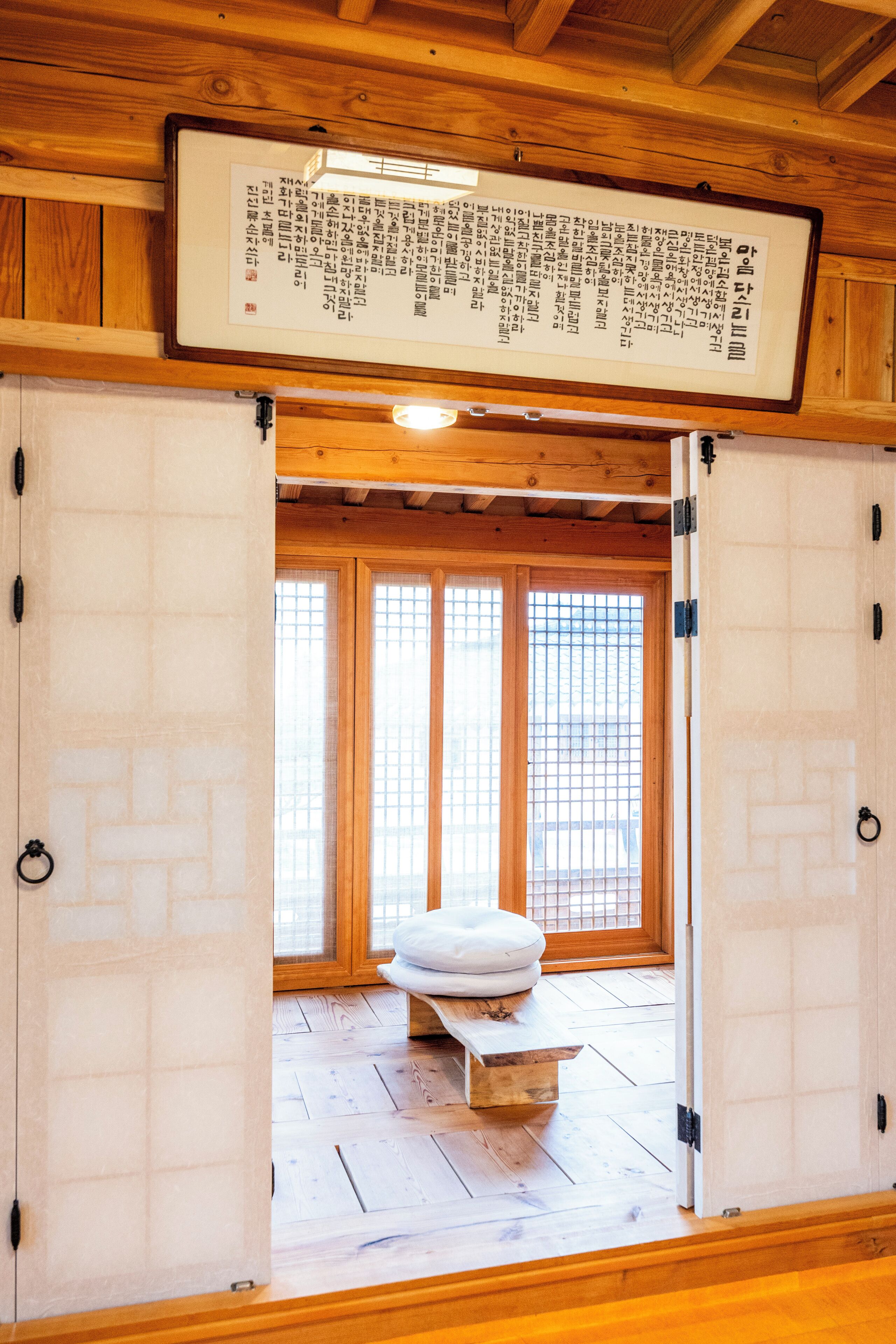 A traditional Japanese room with tatami flooring, a shoji screen door, and a tatami mat with cushions.