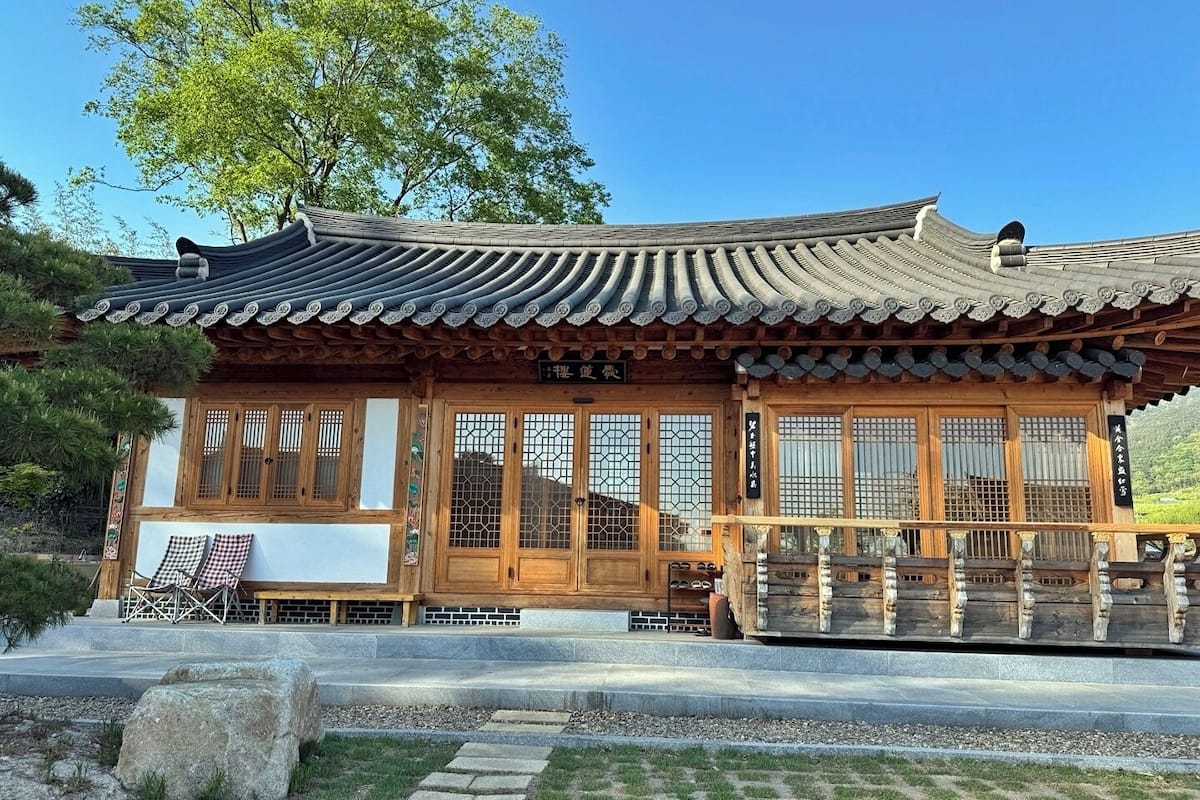 Un bâtiment de style coréen traditionnel, doté d’une architecture en bois, de grandes fenêtres et d’un chemin de pierre menant à l’entrée.