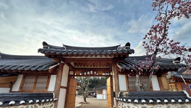 A traditional Korean gate with stone walls and tiled roofs, leading to a courtyard. - Jukrokjungsa hanokstay  (Gurye)
