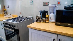 A kitchen with a gas stove, a coffee maker, a blender, and a Samsung microwave. - AZANIAHOMES (Nairobi)