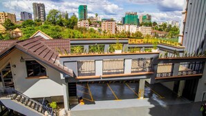 A multi-story building with a rooftop garden, a covered parking area, and a view of the cityscape. - AZANIAHOMES (Nairobi)