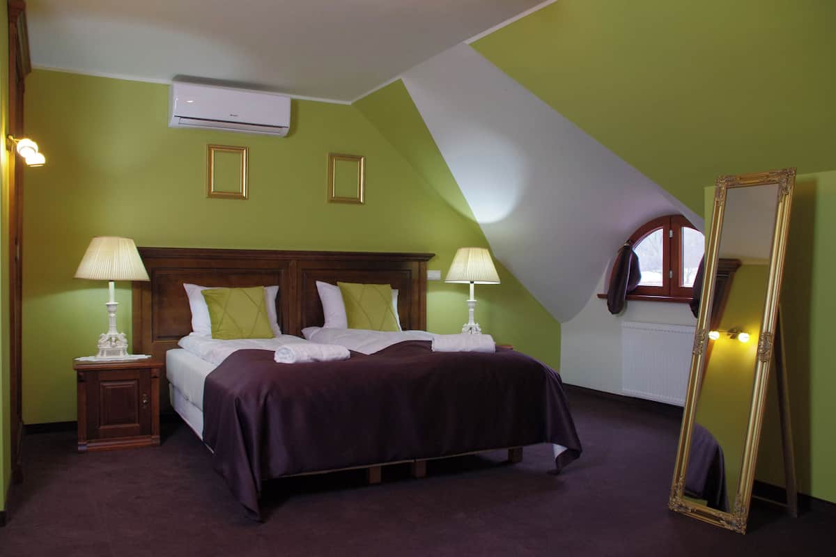 Un dormitorio con una cama, dos mesitas de noche, un espejo y un equipo de aire acondicionado.