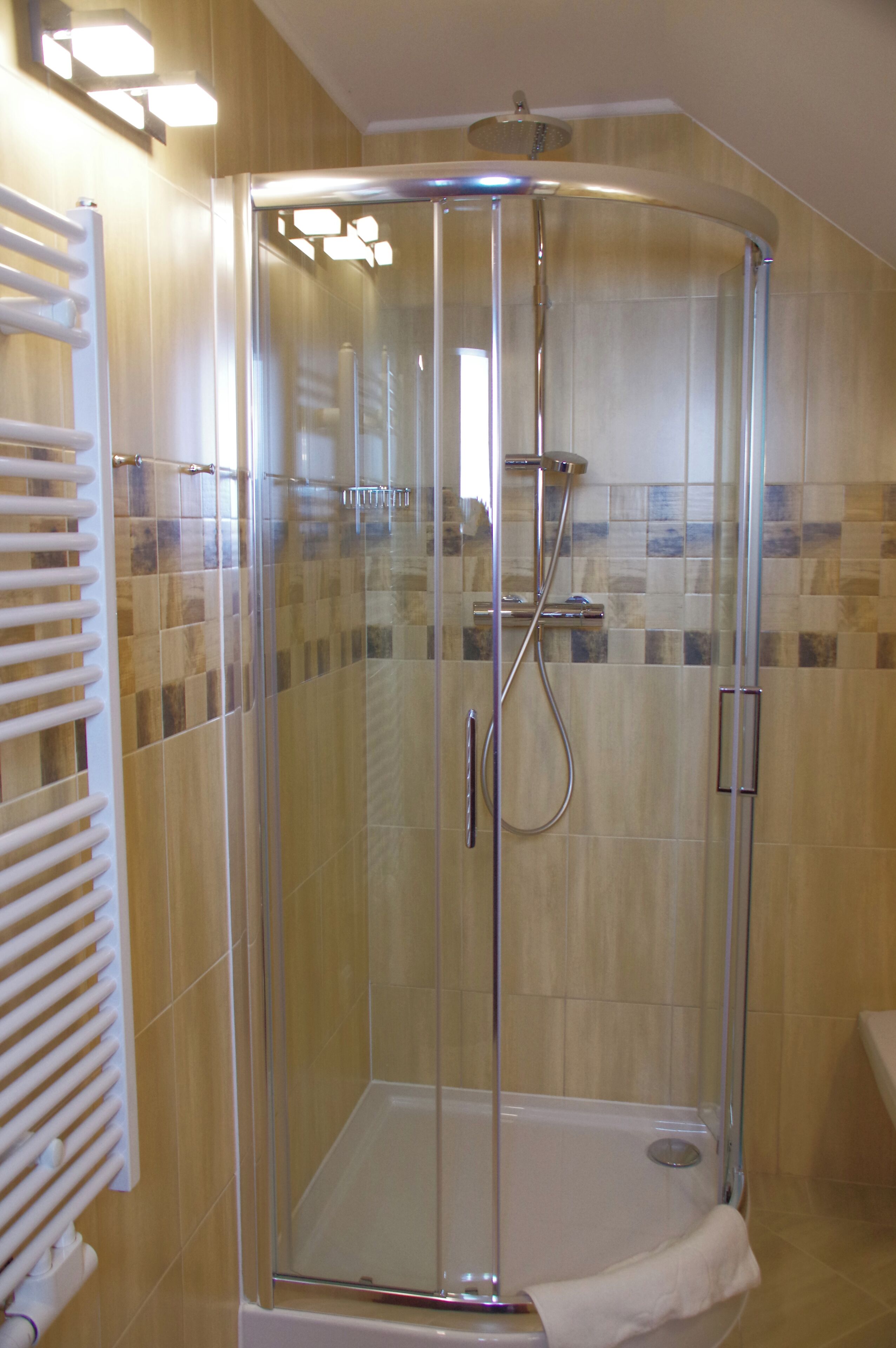 A glass-enclosed shower with a white towel hanging inside.