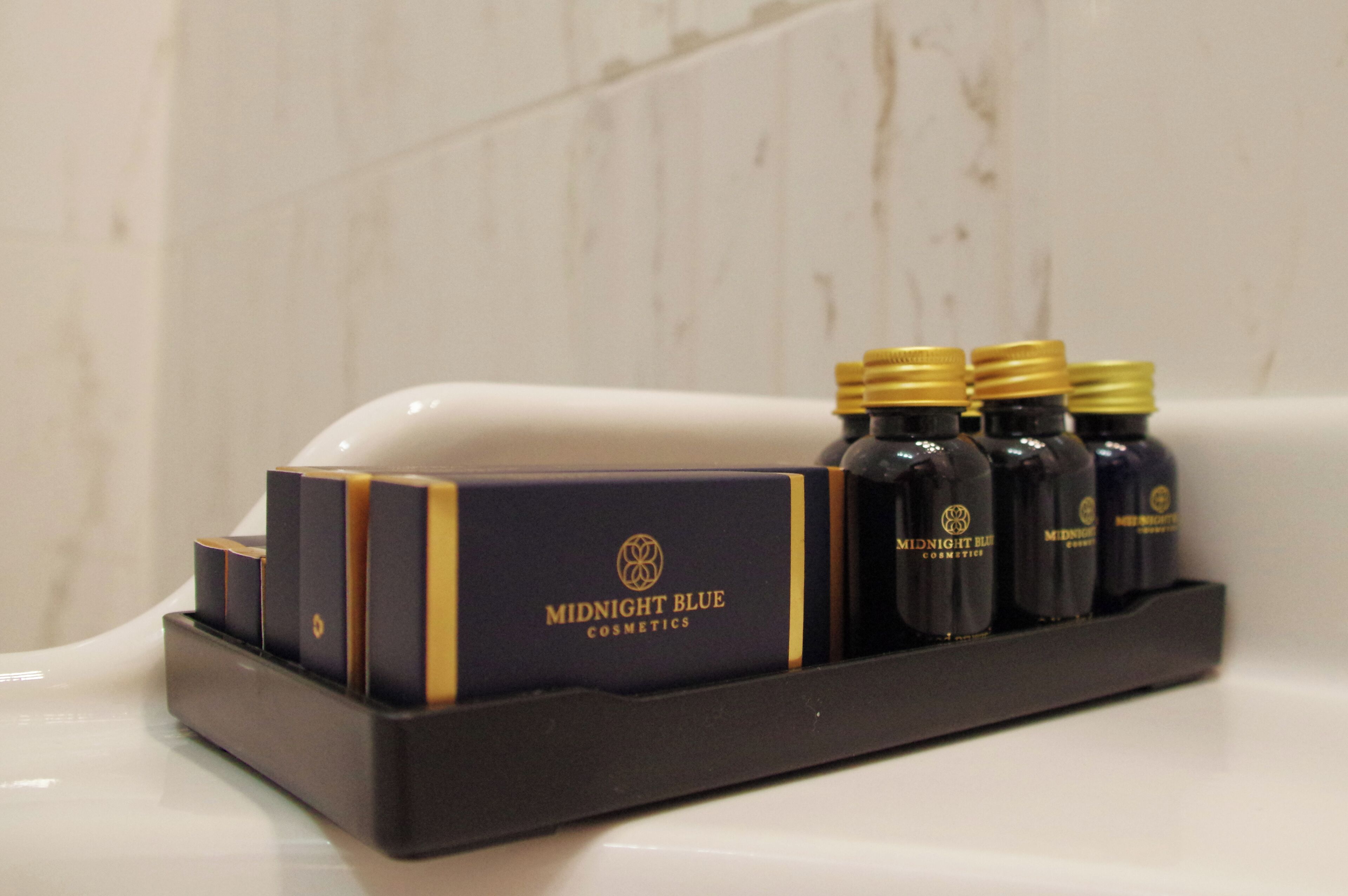 A set of Midnight Blue cosmetics in a black tray on a bathroom sink.