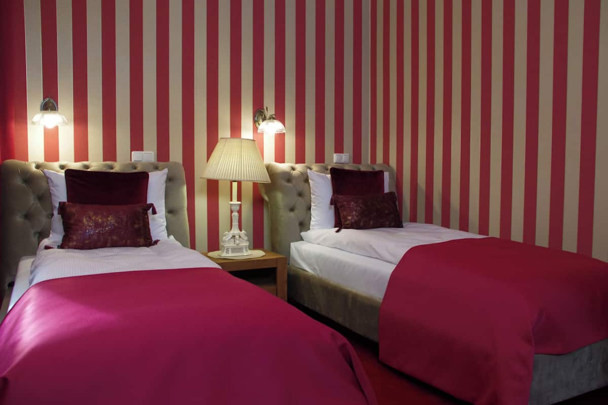 Habitación de hotel con dos camas, papel tapiz a rayas y lámparas de noche.