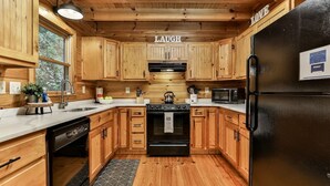 A kitchen with wooden cabinets, a black refrigerator, a stove, and a microwave.