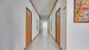 A long, well-lit hallway with wooden doors and a tiled floor, leading to a bright room at the end. - Collection O 90724 Hotel Sinar Sidoarjo (Sidoarjo)