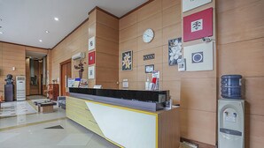 A reception area with a reception desk, a clock, framed pictures, and a water dispenser. - Collection O 90724 Hotel Sinar Sidoarjo (Sidoarjo)