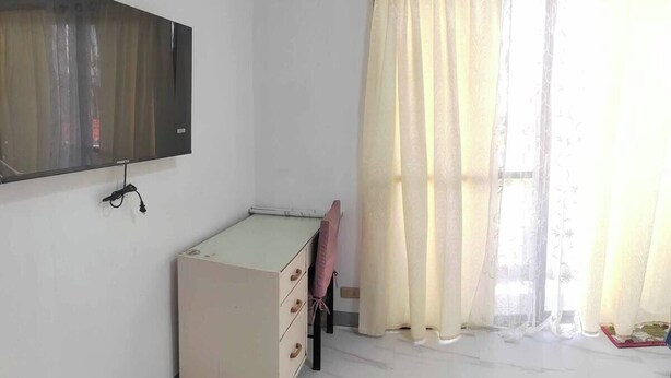 A room with a bed, a desk, a chair, and a TV mounted on the wall.
