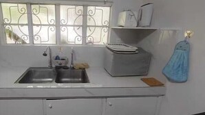 Una cocina con un lavamanos doble, una ventana con rejas decorativas de hierro, una encimera blanca y una toalla azul colgada en la pared.