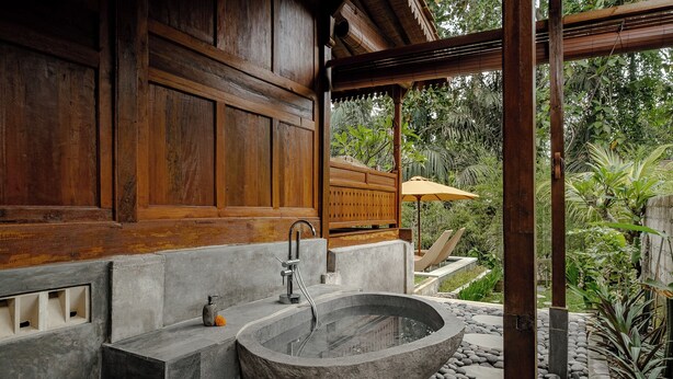 A stone bathtub in a wooden room with a view of lush greenery. - Tegal Beji Ubud Villa (Ubud)