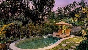 A circular pool with a stone edge, surrounded by lush greenery and a stone wall. - Tegal Beji Ubud Villa (Ubud)