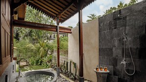 A modern bathroom with a freestanding bathtub, a shower, and a small sink with toiletries. - Tegal Beji Ubud Villa (Ubud)