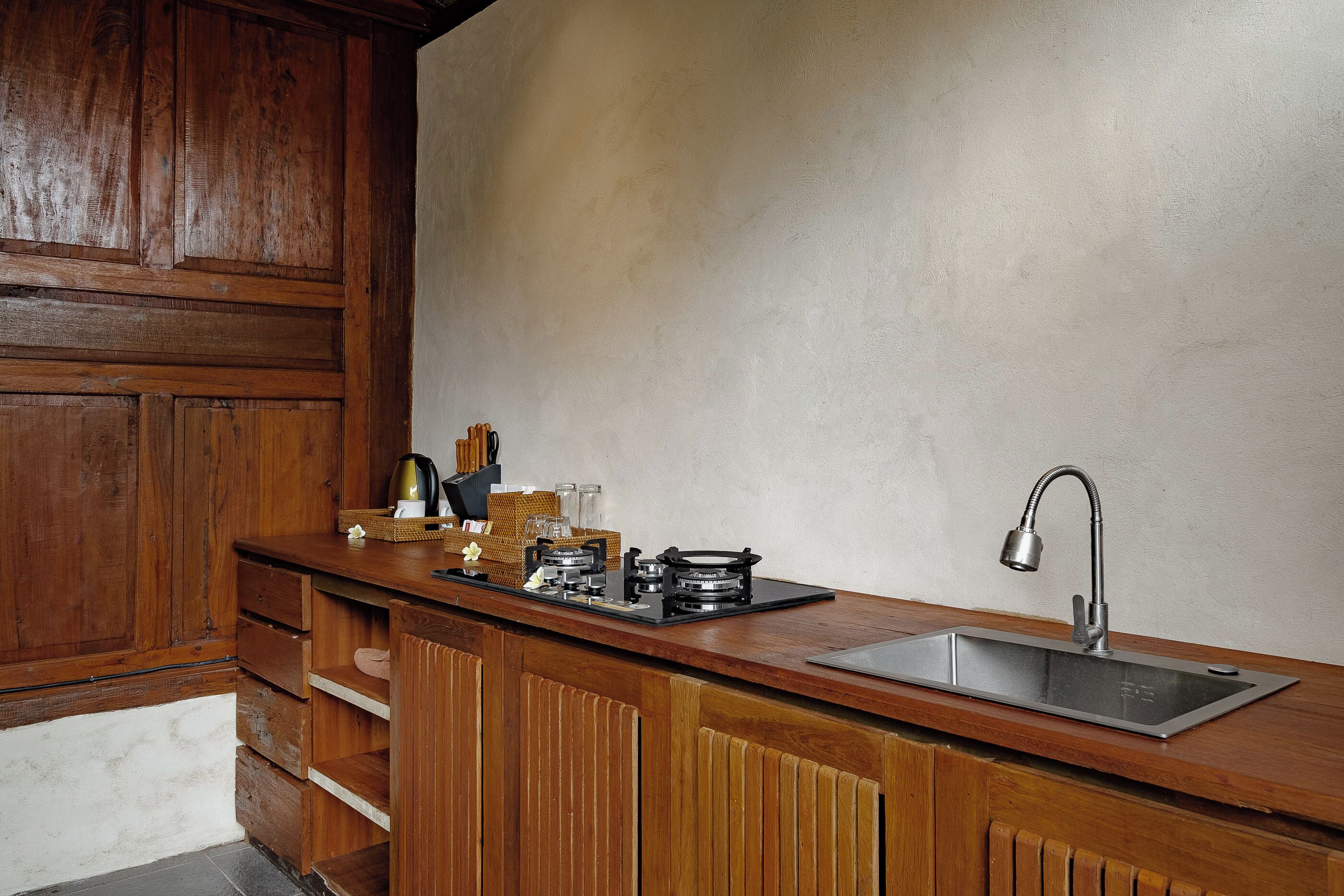 A kitchen with a wooden countertop, a stainless steel sink, and a built-in stove.