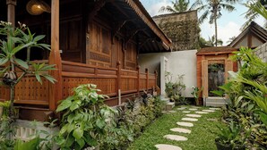 A traditional wooden house with a thatched roof, surrounded by lush greenery and a stone pathway. - Tegal Beji Ubud Villa (Ubud)